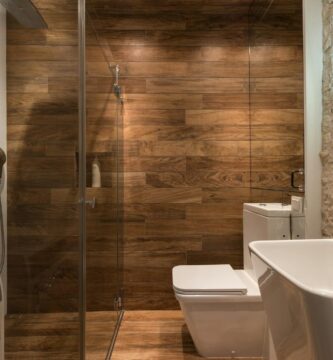 stylish modern bathroom interior design with glass shower enclosure toilet bowl and sink under oval mirror
