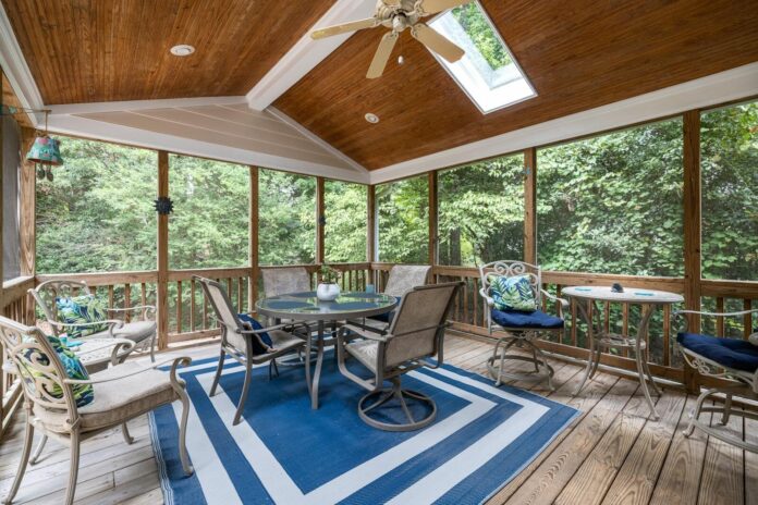 Photo by Curtis Adams Spacious indoor terrace with elegant patio furniture and forest view, ideal for relaxation.