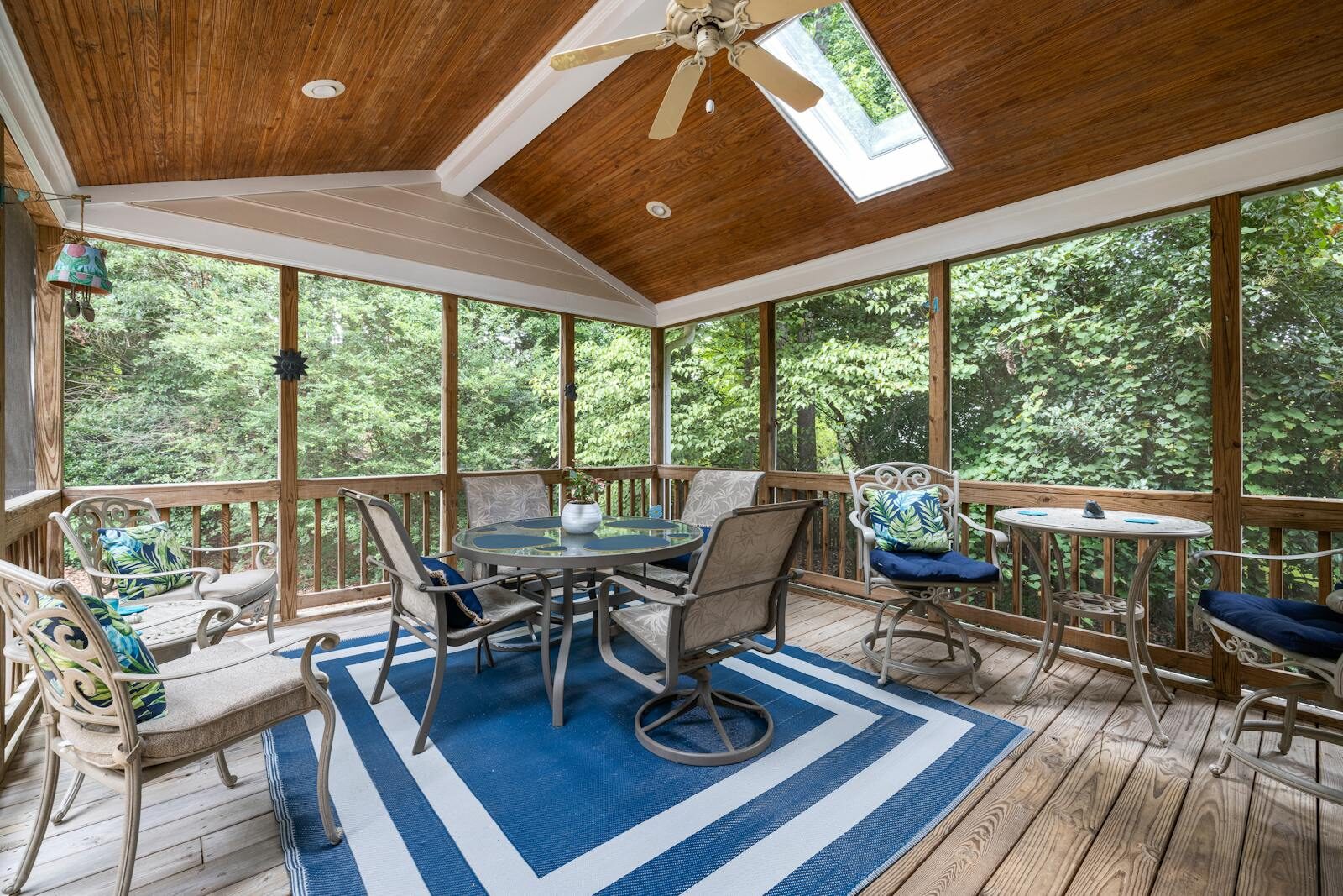 Spacious indoor terrace with elegant patio furniture and forest view, ideal for relaxation.