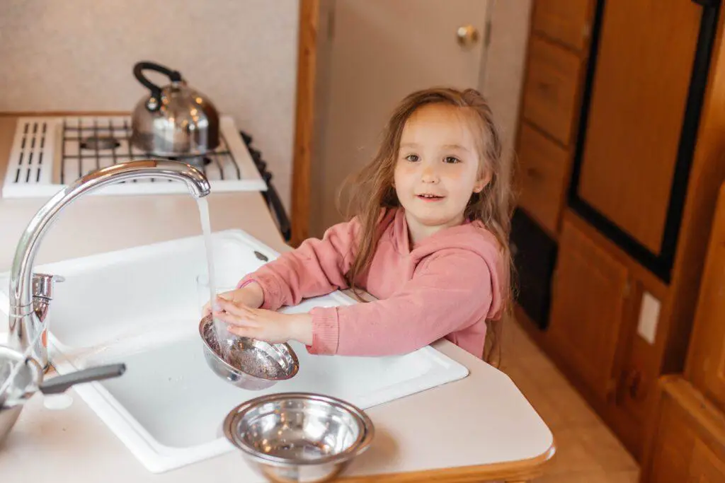 a little girl washes the dishes in the kitchen in 2022 02 10 00 19 30 utc