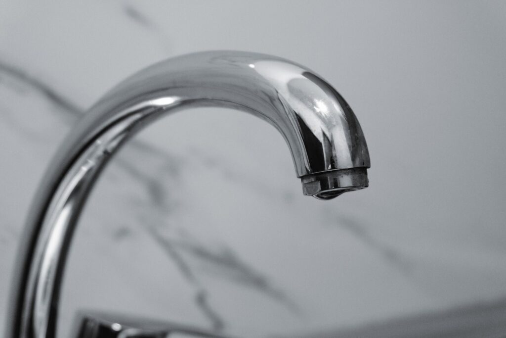 Close-up of a chrome faucet with a marble background, highlighting modern interior design.