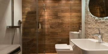 stylish modern bathroom interior design with glass shower enclosure toilet bowl and sink under oval mirror