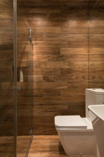 Stylish modern bathroom interior design with glass shower enclosure toilet bowl and sink under oval mirror