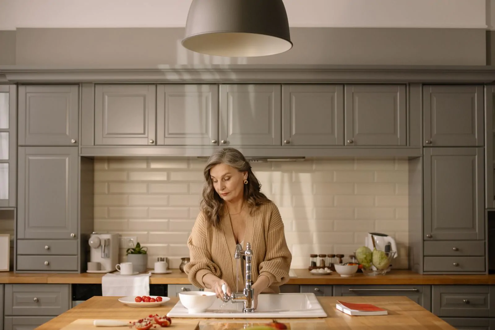 senior woman at kitchen sink preparing ingredients amidst a modern setting, for cooking.