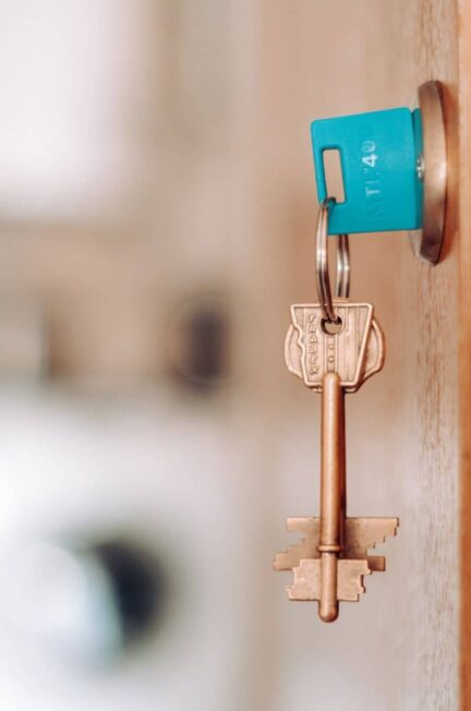 A brass key with a blue plastic tag in a door lock indoors.