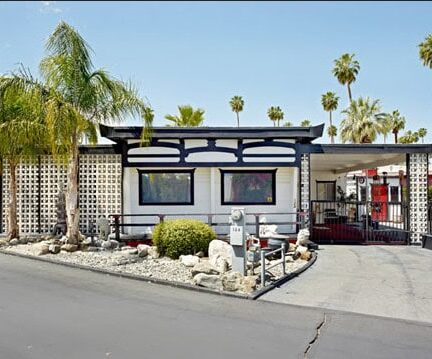 Modern mobile home with desert landscaping and palm trees in Palm Springs.